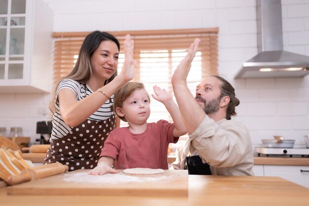 Mamá y papá en la cocina de la casa con sus hijos pequeños se divierten horneando pan