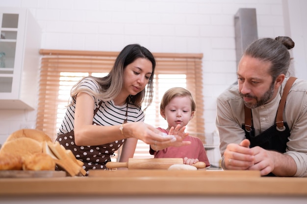 Mamá y papá en la cocina de la casa con sus hijos pequeños se divierten horneando pan