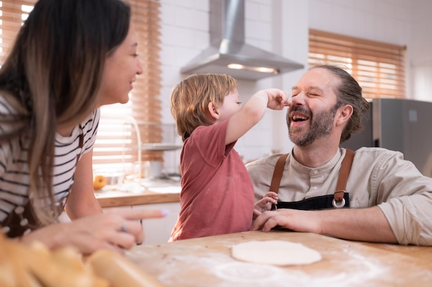 Mamá y papá en la cocina de la casa con sus hijos pequeños Pasan un buen rato horneando pan y preparando la cena juntos