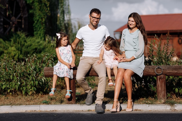 Foto mama, papa, die töchter umarmen, sitzen gerne draußen und schauen sich die natur an. junge familie, die zeit zusammen im urlaub, im freien verbringt. muttertag, vatertag, babytag.