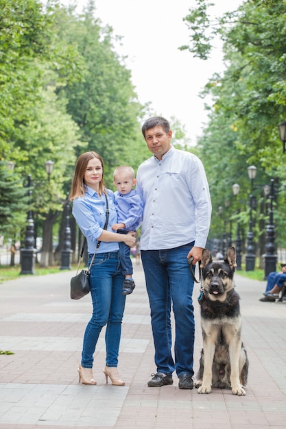 Mamá, papá e hijo en un paseo con un perro pastor en la ciudad.