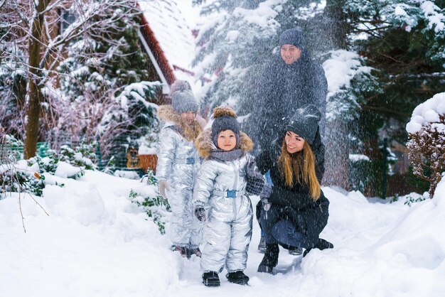 Mamá y papá de familia guapos y su pequeña hija linda con hijo se divierten al aire libre en invierno ...