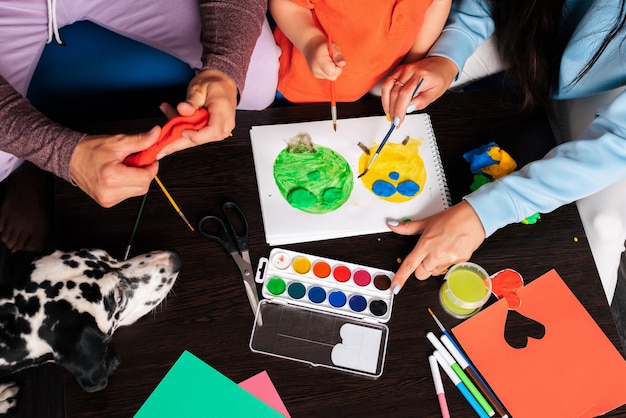 Mamá, papá, hijo y su perro juegan con plastilina y pintura en casa