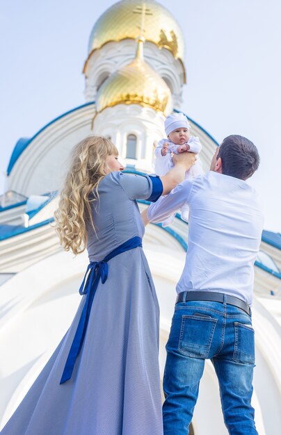 Mamá y papá sostienen al bebé en la iglesia.