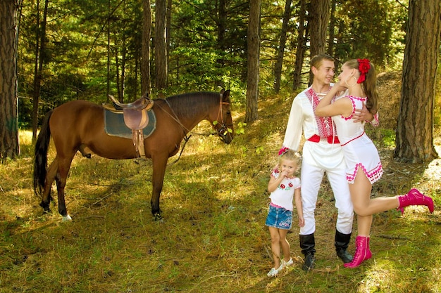 Mamá y papá ucranianos e hija en el bosque con un caballo