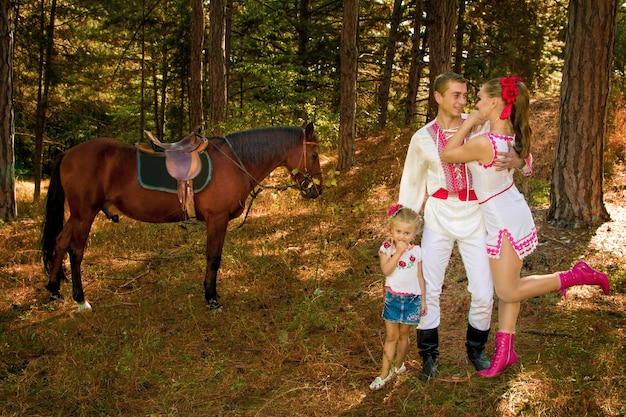 Mamá y papá ucranianos e hija en el bosque con un caballo