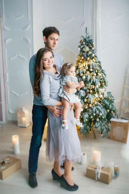 Mama Papa und Baby umarmen und freuen sich am Weihnachtswinterabend in der Nähe des Neujahrsbaums