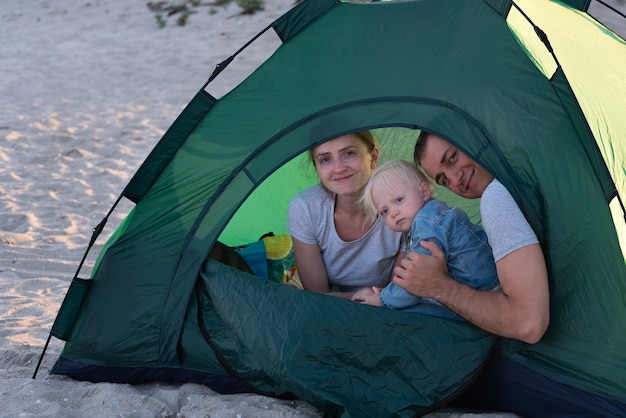 Mama, Papa und Kind im Touristenzelt auf dem Campingplatz. Familienurlaub.