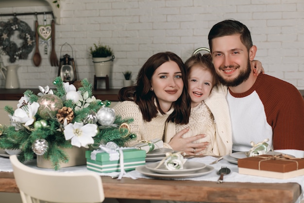 Mama, Papa und schöne Tochter sitzen an Weihnachten am Küchentisch. Weihnachtsferien-Konzept