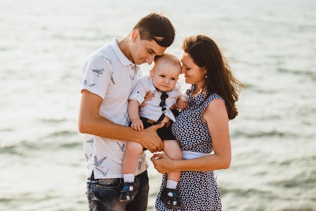 Mama, Papa und Sohn. Die Familie spaziert am steinigen Strand am Meer entlang.