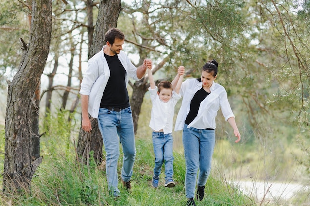 Mama, Papa und Sohn gehen im grünen Gras spazieren