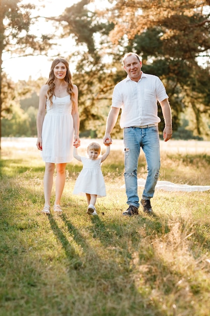 Mama, Papa und Tochter gehen im Park in der Natur spazieren