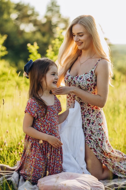 Mamá peina el cabello de su hija en la naturaleza Mujer con dos hijas sentada en el parque