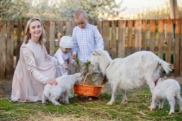 Mamá con una pequeña hija alimenta a una cabra.