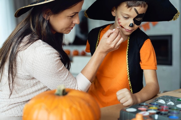 Mamá pinta la cara de su hijo a la fiesta de Halloween