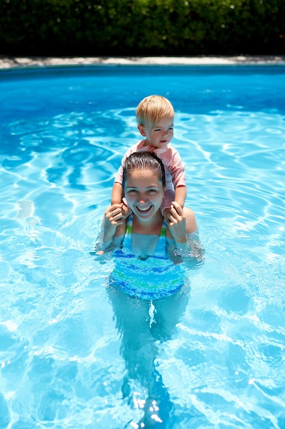 Mamá se para en la piscina con una niña sobre sus hombros.