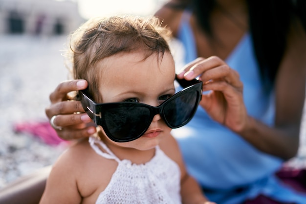 Mamá le pone gafas de sol a una niña