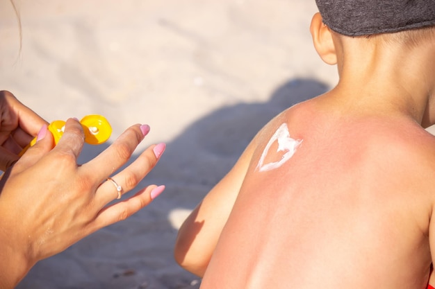 Mamá pone protector solar en la espalda de Sin en forma de corazón.