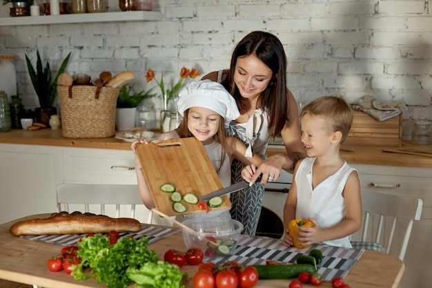 Mamá prepara el almuerzo con los niños. Una mujer le enseña a su hija a cocinar de su hijo