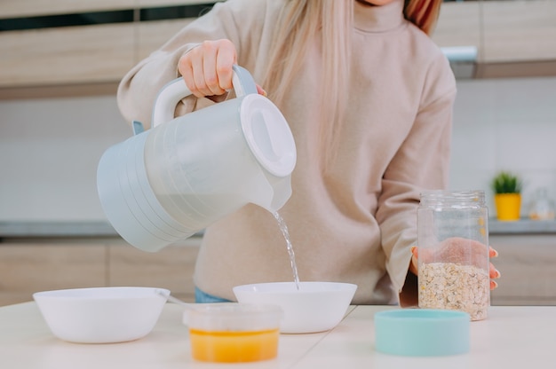 Mamá prepara avena con miel en la cocina.