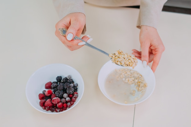 Mamá prepara avena con miel y frutas en la cocina.