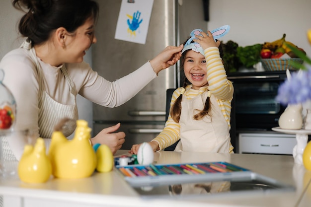 Mamá quita la máscara del conejo de Pascua de la cara de sus hijas para ver su hermosa sonrisa