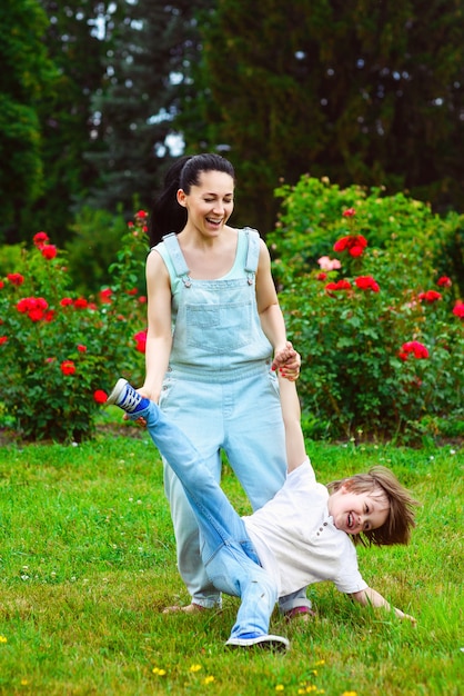 Mamá riendo rueda sobre la espalda del hijo pequeño en el parque