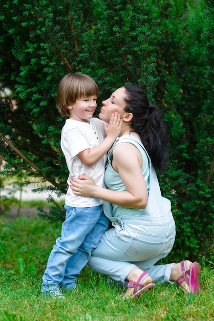 Foto mamá riendo rueda sobre la espalda del hijo pequeño en el parque