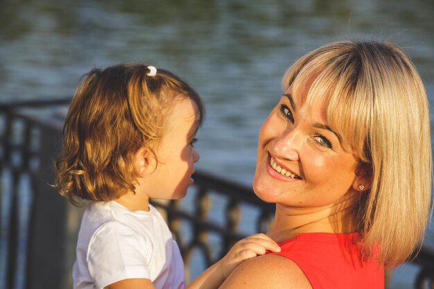 Mamá rubia hermosa en una camiseta roja con su hija. de cerca