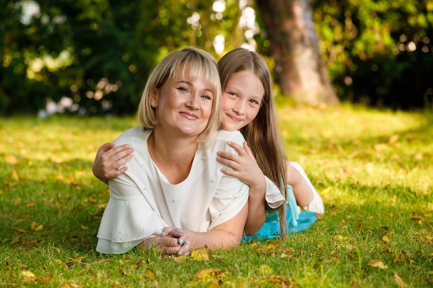 Mamá rubia con hija en el parque en verano en tiempo soleado