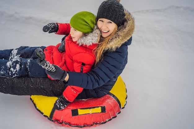Mama-Sohn-Fahrt auf einem aufblasbaren Winterschlitten Tubing Winterspaß für die ganze Familie