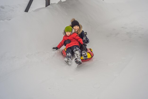 Mama-Sohn-Fahrt auf einem aufblasbaren Winterschlitten Tubing Winterspaß für die ganze Familie