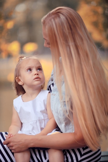 Mamá sosteniendo a su hija en sus brazos fotos de otoño en el parque amarillo