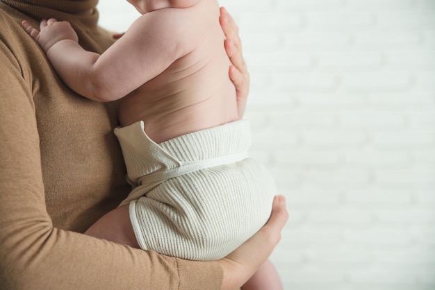 mamá sostiene al bebé en sus brazos en pañales de algodón reutilizables