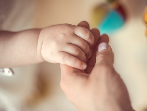 Foto mamá sostiene al niño de la mano.