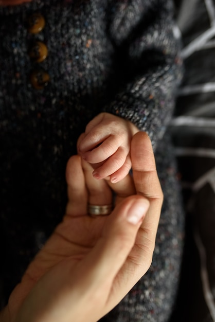 Mamá sostiene la pequeña mano de su hijo recién nacido.