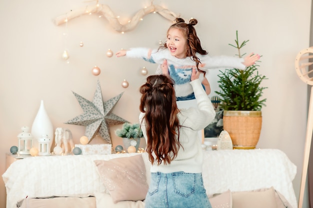 Mama spielt und erbricht Tochter auf dem Hintergrund eines Weihnachtsbaums an Silvester