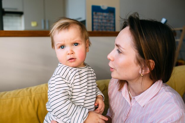 Mama spielt zu Hause mit kleinem Kind auf der Couch viel Spaß