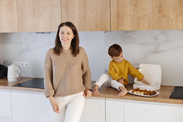 Mama steht neben einem kleinen Jungen, der neben türkischen Süßigkeiten auf der Küchentheke sitzt