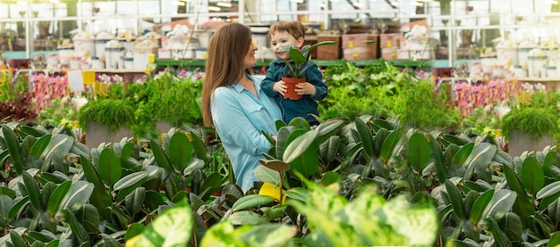 Mamá y su bebé en una tienda de plantas eligen plantas. Jardinería en invernadero. Jardín botánico, cultivo de flores, concepto de industria hortícola