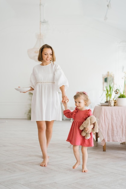 Mamá y su hija de tres años van a desayunar por la mañana La madre de la novia sostiene un plato y sostiene a la niña por el asa