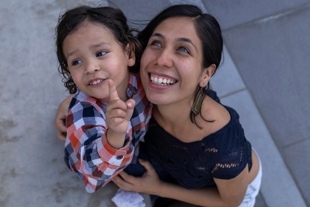 Mamá y su hijo latinoamericano sentados en un banco mostrando su amor con sonrisas y felicidad Concepto y familia del día de la madre