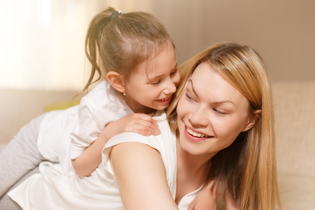 Mamá y su niña linda hija están jugando, sonriendo y abrazándose