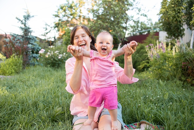 Mamá y su pequeña hija se ríen y se divierten al aire libre en el jardín exterior.