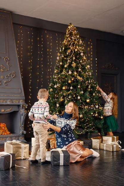 Mamá y sus dos hijos decoran el árbol de Navidad