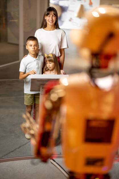 Mamá con sus hijos interactúan con el robot en el museo de ciencias