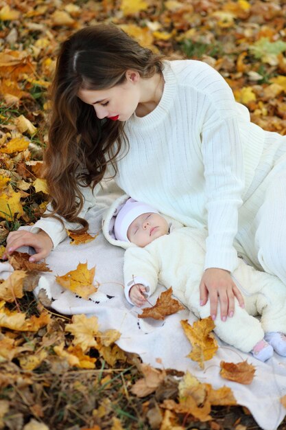 Mamá tiene a su pequeña hija en el bosque de otoño