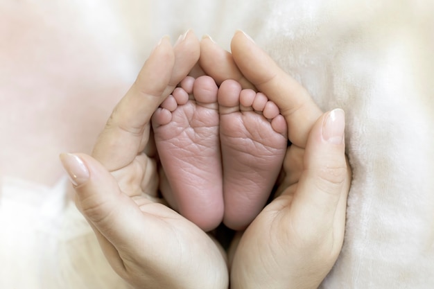 Mamá tiene en sus manos los pies de un bebé recién nacido