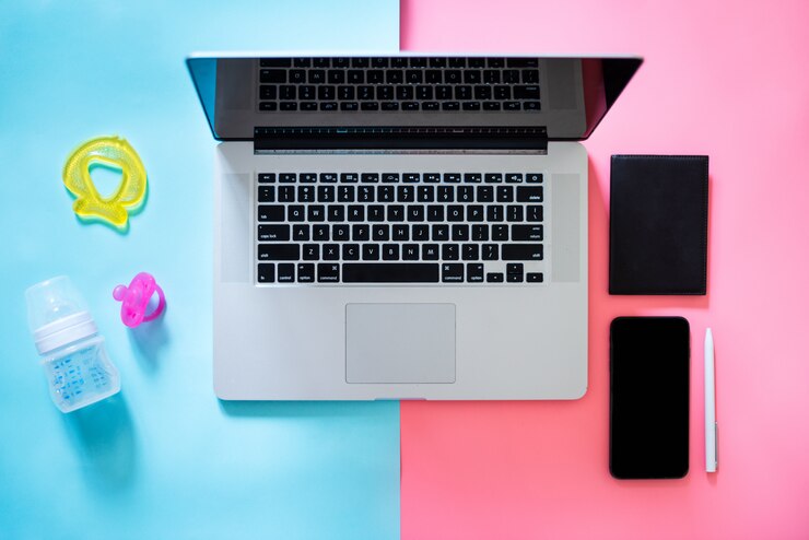 Foto mamá trabajadora vista superior flatlay de artículos de bebé del lugar de trabajo y computadora portátil con teléfono