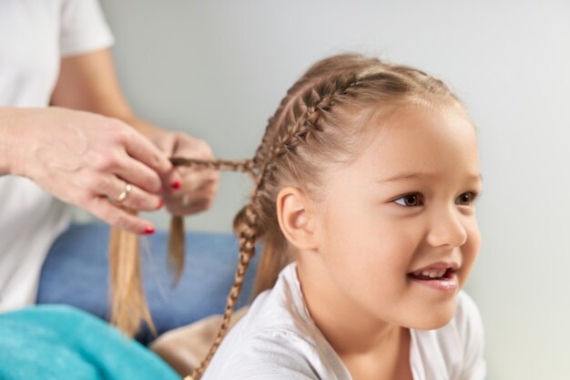 Mamá trenza coletas a su linda hija